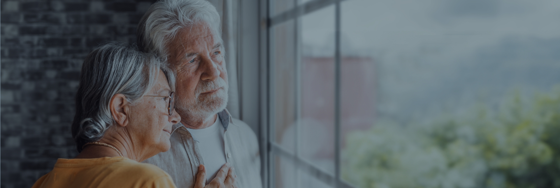 a senior couple lean against each other while looking out the window